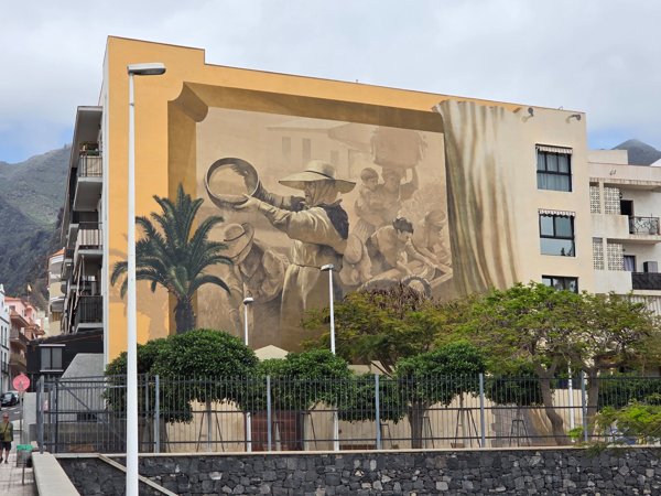Ein riesiges Wandgemälde an einem Wohnhaus in Adeje zeigt traditionelle kanarische Szenen und Handwerk.