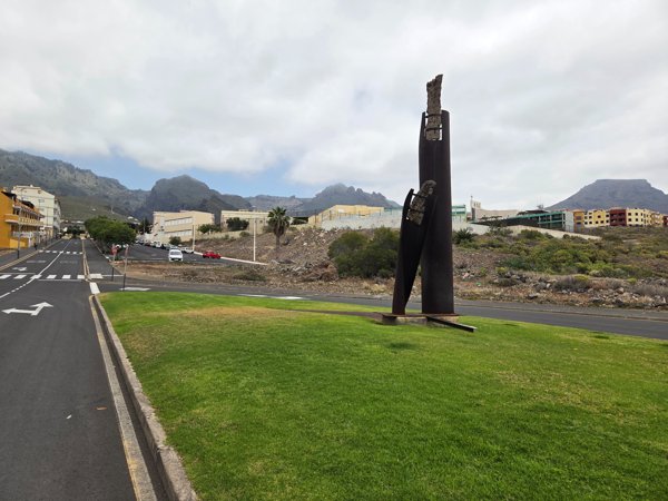 Ein modernes Kunstwerk aus Stahlplatten am Stadtrand von Adeje mit Blick auf das Gebirge.